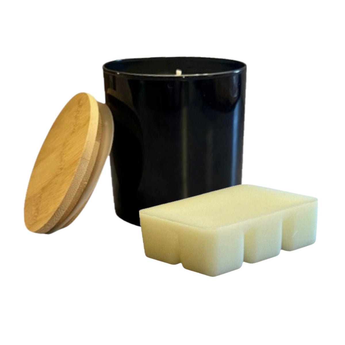 Black glass candle with wooden lid labeled 'The Paisley Candle Company – Fresh Cut Grass' placed beside a decorative faux grass sphere.
