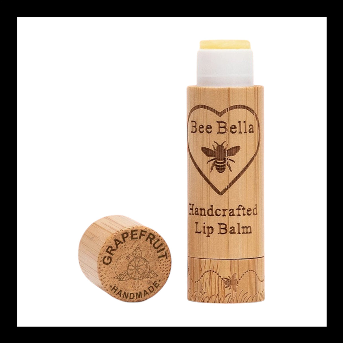 Bee Bella Handcrafted Lip Balm in eco-friendly bamboo packaging, featuring an engraved bee and heart design. The cap, placed beside the tube, is engraved with 'Grapefruit Handmade' alongside a citrus illustration.
