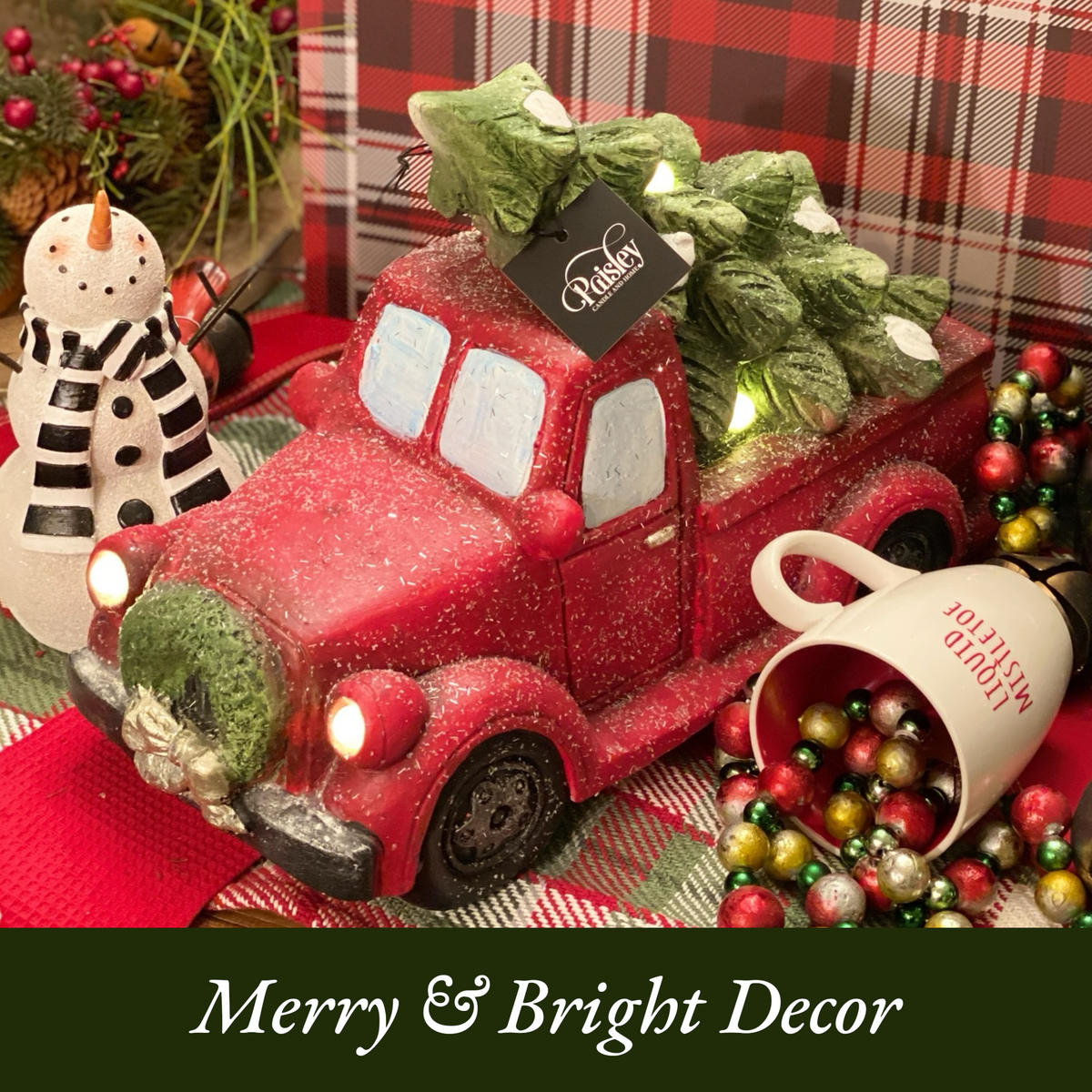 Festive red truck Christmas decoration with tree and lights, surrounded by ornaments and holiday decor.