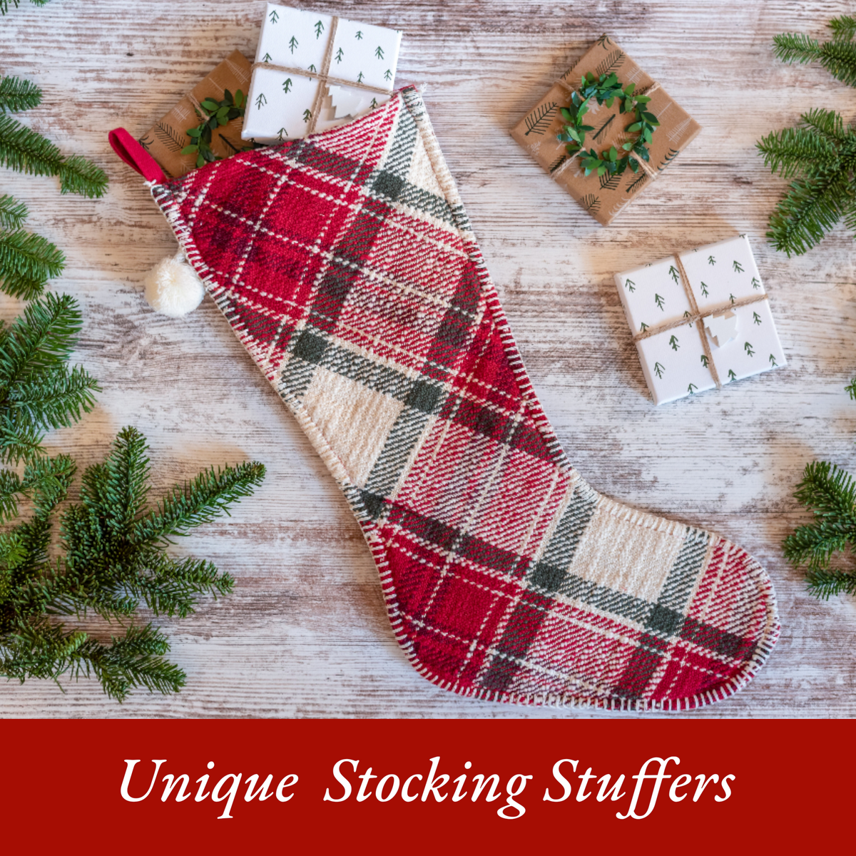 Red plaid Christmas stocking filled with small wrapped gifts and surrounded by evergreen branches.