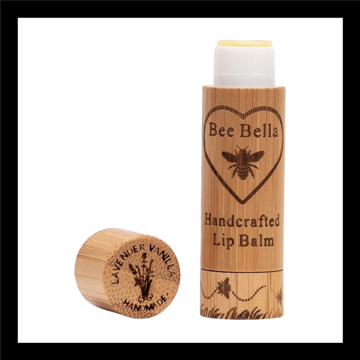 Bee Bella Handcrafted Lip Balm in eco-friendly bamboo packaging, featuring an engraved bee and heart design. The cap, placed beside the tube, is engraved with 'Lavender Vanilla Handmade' alongside a lavender illustration. 