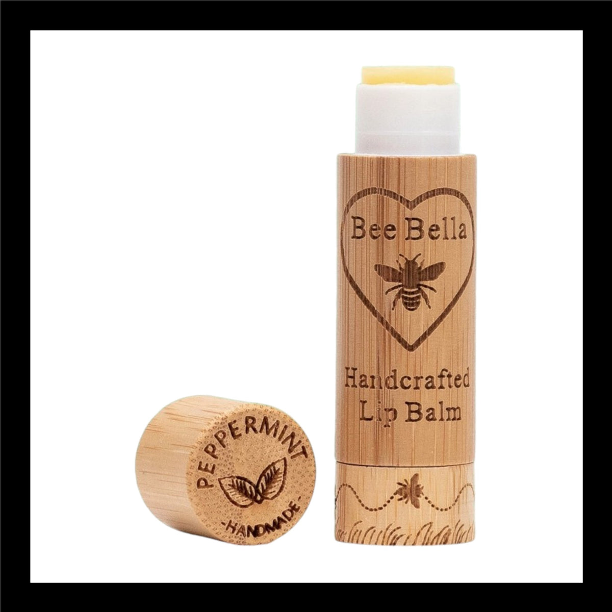 Bee Bella Handcrafted Lip Balm in eco-friendly bamboo packaging, featuring an engraved bee and heart design. The cap, placed beside the tube, is engraved with 'Peppermint Handmade' alongside a mint leaf illustration.