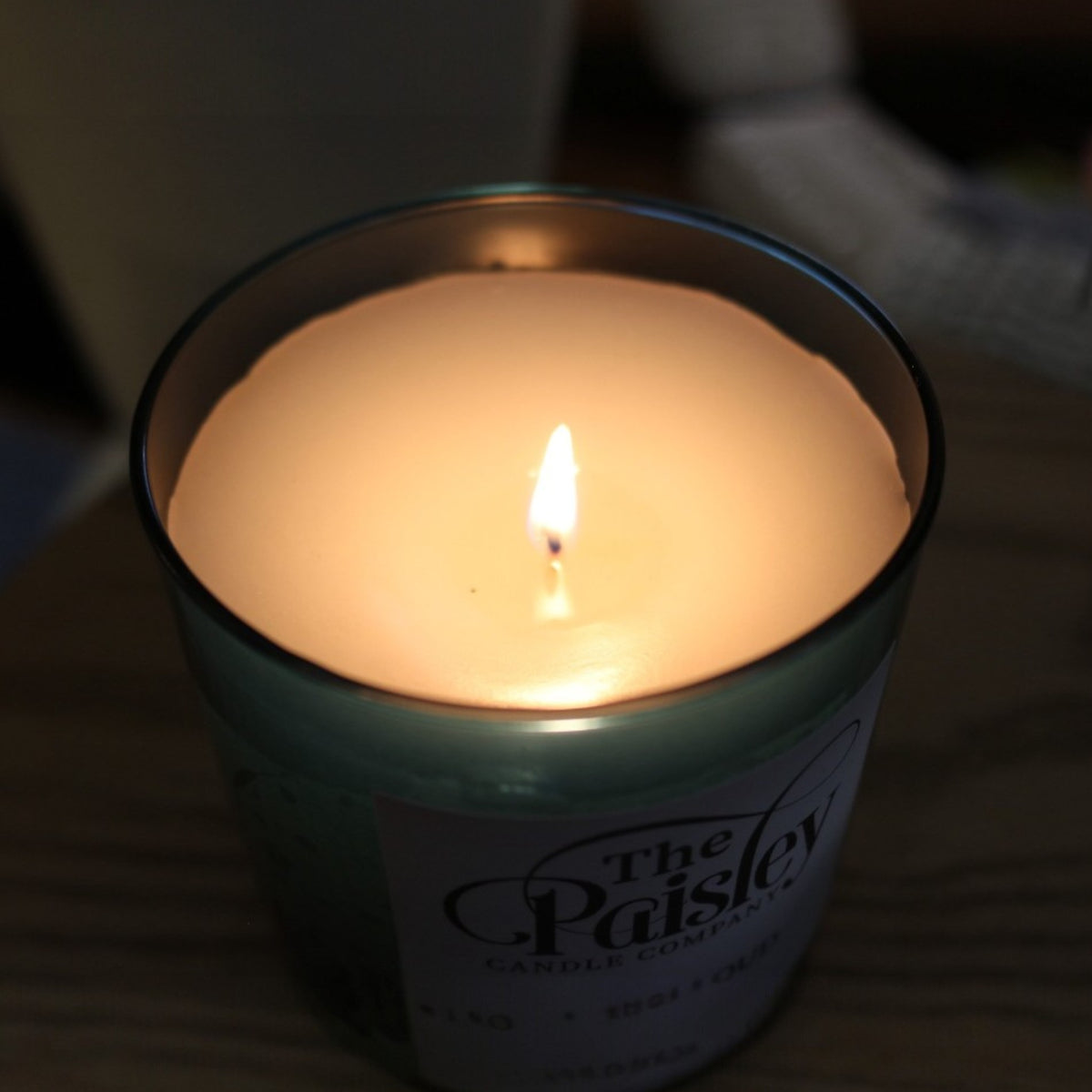 Storm Cloud amber candle close-up with lit flame and smooth wax surface in warm low-light setting