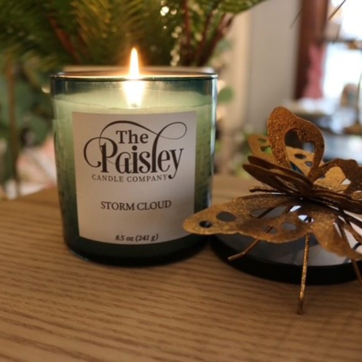 Storm Cloud amber candle by Paisley Candle Company lit with warm glow on wood surface in cozy home setting