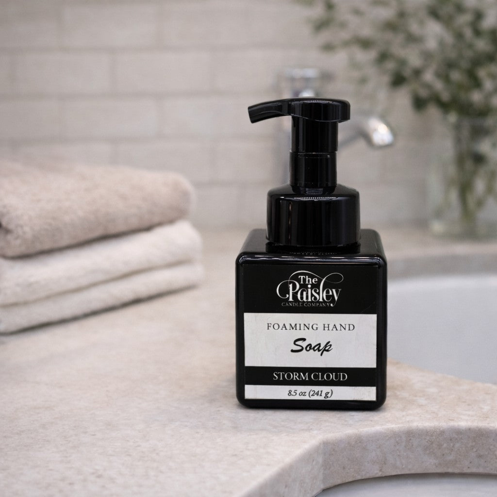 Storm Cloud foaming hand soap by Paisley Candle Company on bathroom sink with folded towels and modern decor