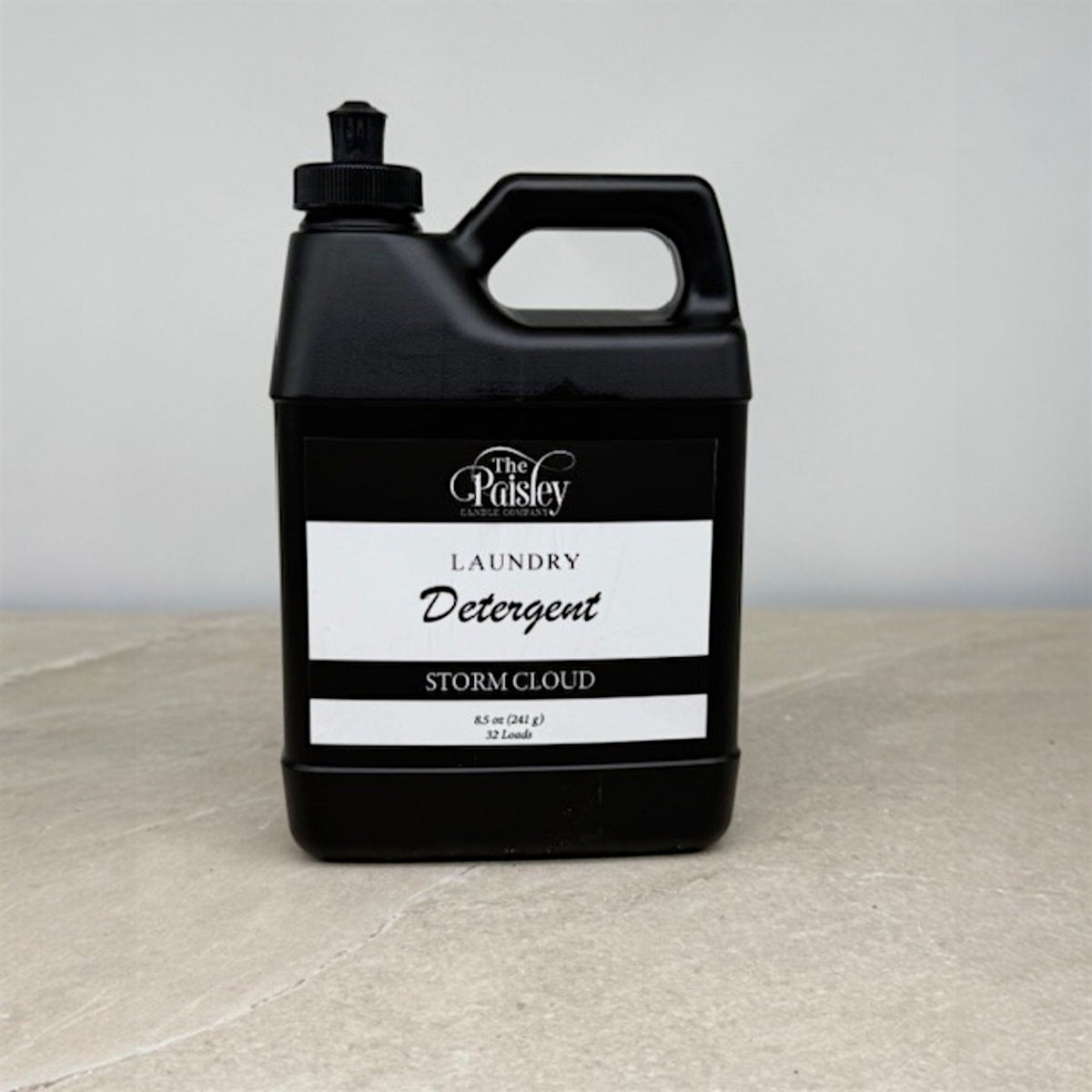 Storm Cloud laundry detergent by Paisley Candle Company in matte black bottle on neutral background