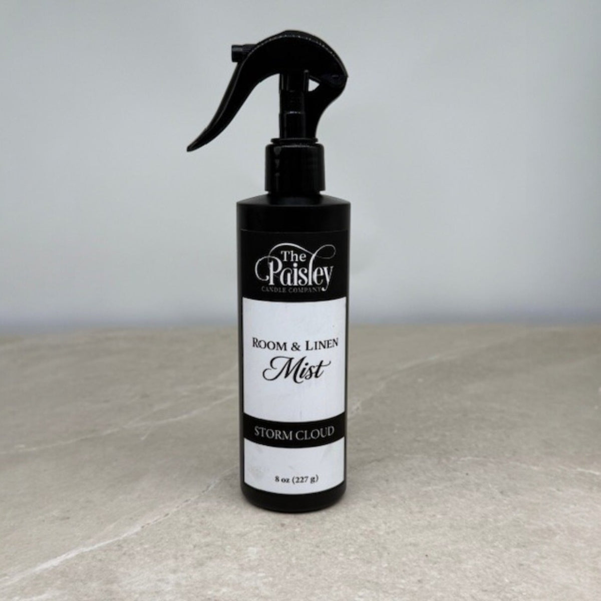 Storm Cloud room and linen mist by Paisley Candle Company in black spray bottle on neutral background