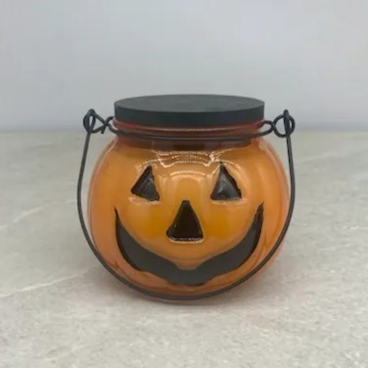 Traditions candle with warm apple, orange, cinnamon and clove fragrance notes in orange Jack-O'-Lantern jar with black lid. 